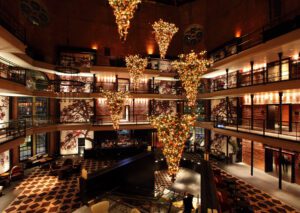 A stylish hotel lobby in Boston with modern decor, warm lighting, and upside-down Christmas trees, a festive twist near Beacon Hill, Massachusetts.
