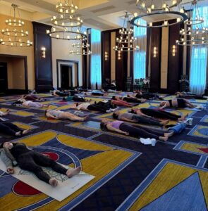 People are lying on yoga mats in a Boston hotel’s elegant room, enjoying group relaxation or meditation as part of their fitness routine.