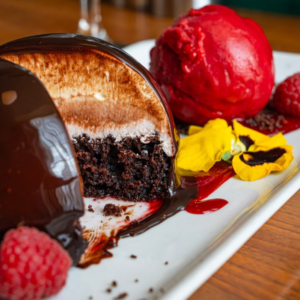 A chocolate mousse dome with a glossy glaze, cake center, and raspberry sorbet—an elegant Beacon Hill-inspired dessert near Boston Common.