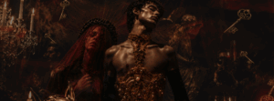 Two people in ornate, gold costumes pose dramatically with red lighting; keys and chandeliers appear in the dark, mystical background.