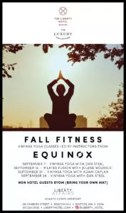 A person practices yoga at sunrise on a hotel rooftop in Boston, promoting fall fitness classes at The Liberty Hotel.