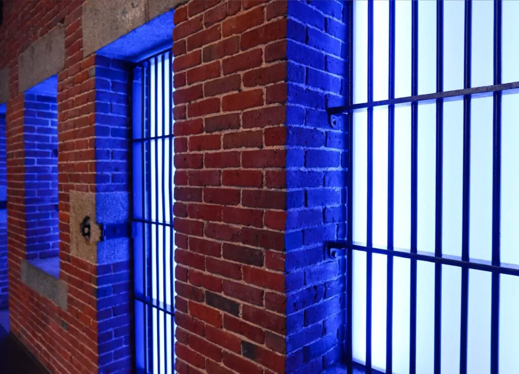 Brick wall with barred windows illuminated by blue light, evoking a luxury hotel vibe in Beacon Hill with a dramatic, moody ambiance.