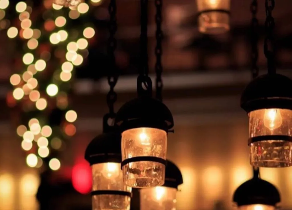 Luxury hanging lanterns glow warmly in focus, with soft, colorful bokeh lights blurred in the background—Beacon Hill elegance captured in a photo.