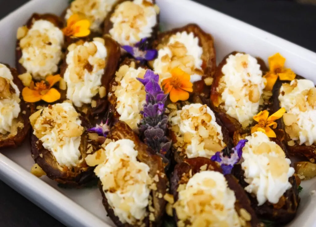 Stuffed dates with cream cheese, nuts, and edible flowers—an elegant treat perfect for a luxury hotel in Beacon Hill.