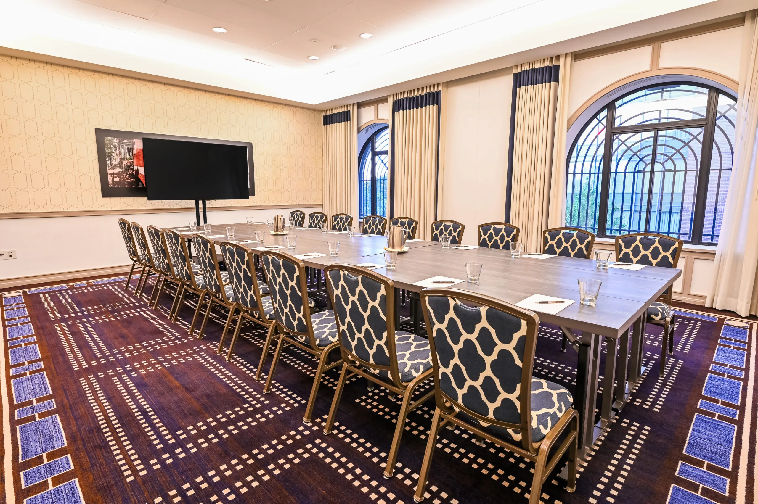 U-shaped conference room near Boston Common with patterned chairs, TV screen, large windows, notepads, and decorative carpet in Massachusetts.